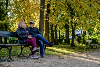 Umirovljenici sjede i razgovaraju na klupi u parku.
