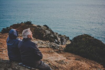 Par umirovljenika sjedi uz obalu i gleda more.