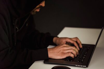 Haker s kapuljačom koristi laptop.