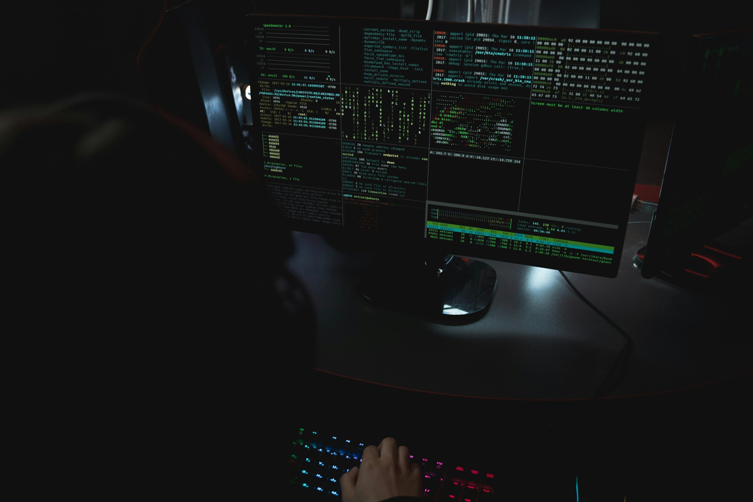 Haker s kapuljačom sjedi u mraku i koristi računalo za kibernetički napad.