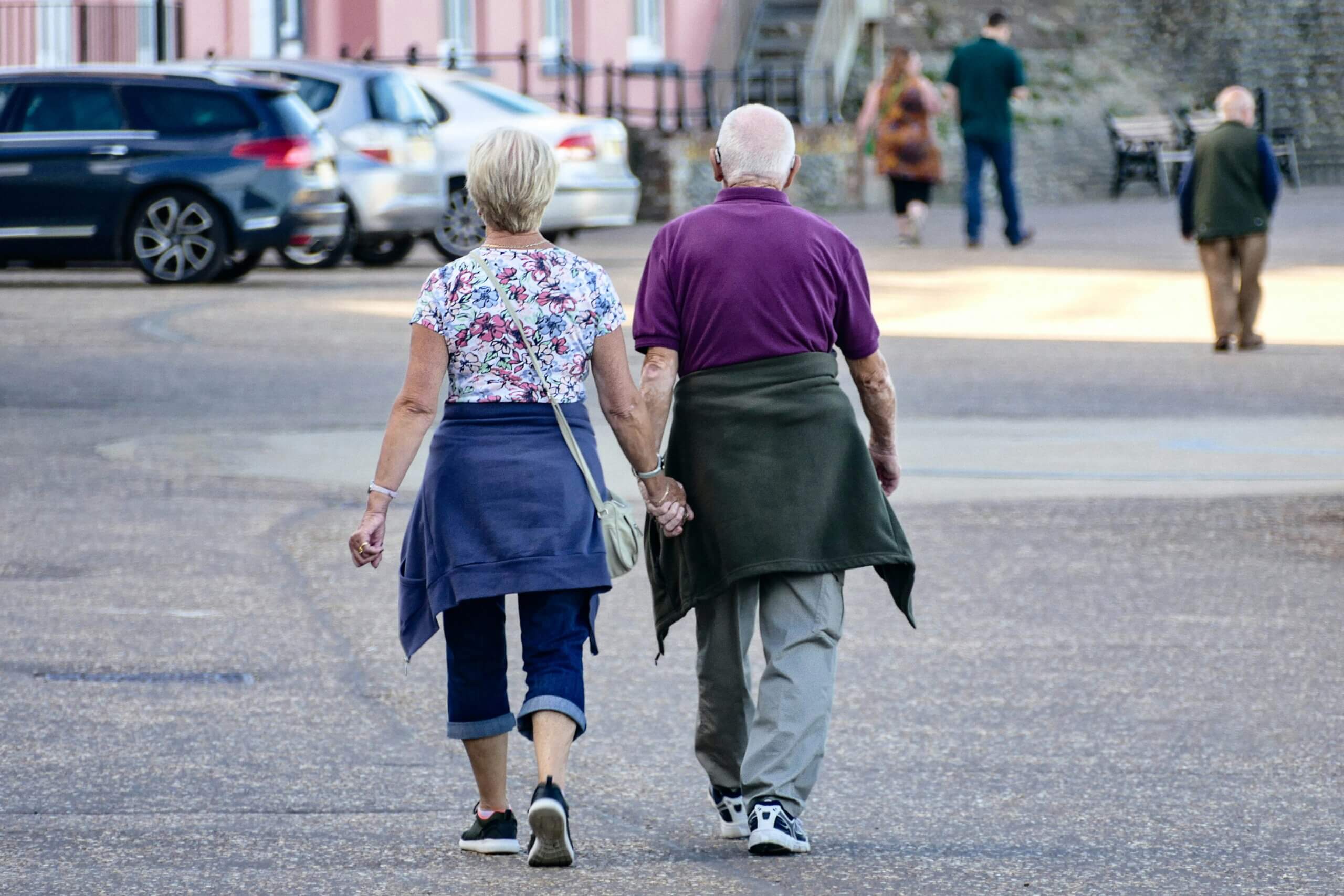 Umirovljenički par se drži za ruke dok šetaj ulicom.