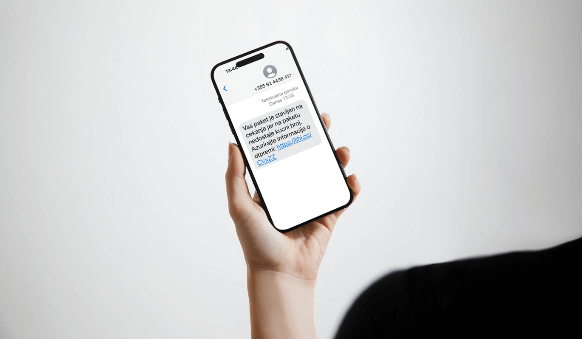 Ruka s mobitelom u ruci na kojem je lažna SMS poruka